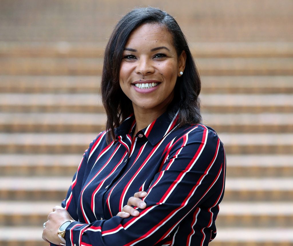 Seminar speaker, Nicole Sparks, PhD, standing in front of a stairway, while wearing a striped shirt