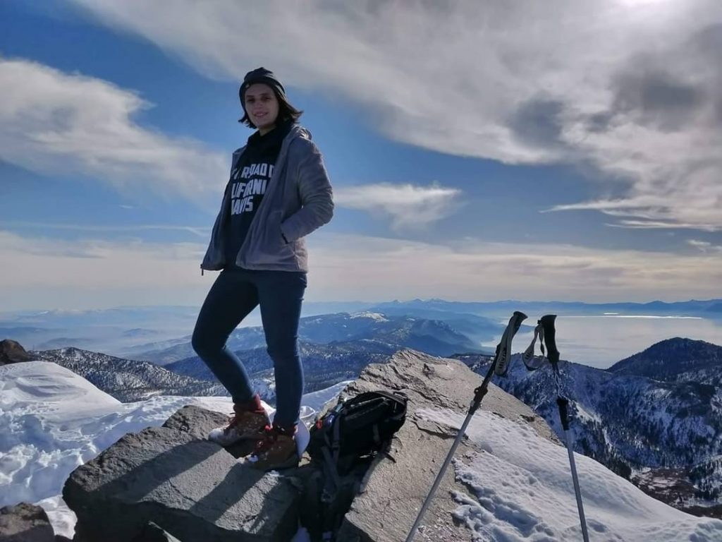 ITEHP student, Laura Jameson, with hiking gear, standing on top of a snowy mountain