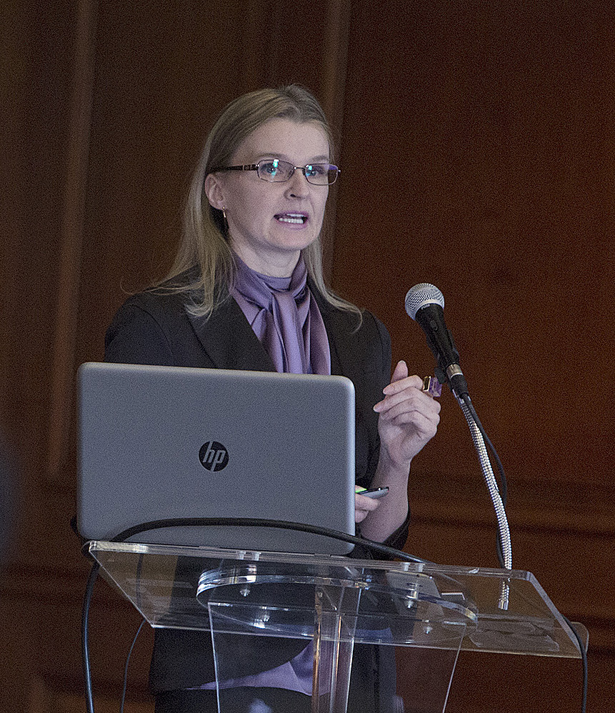 Seminar speaker, Dr. Julia Kravchenko, speaking at a podium, wearing a black suit jacket over a purple top