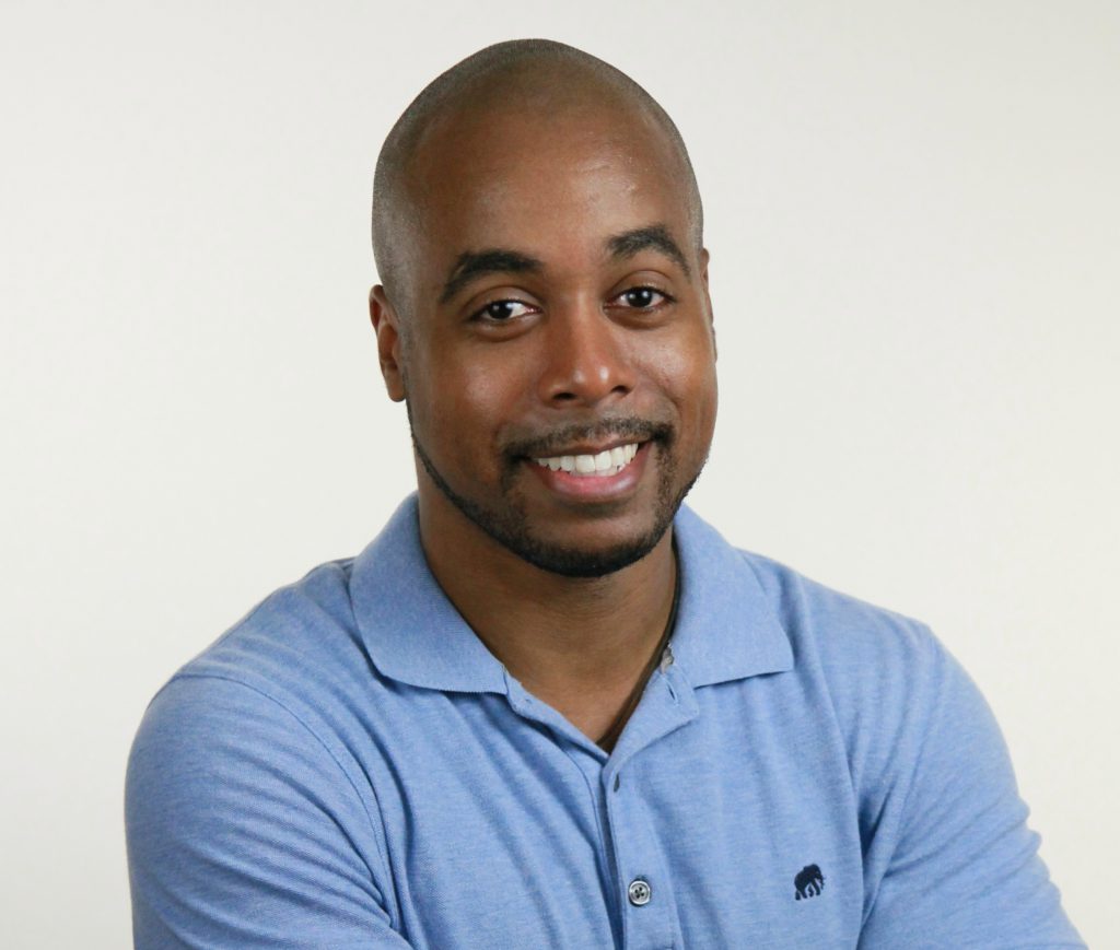 Headshot of Dr. E. Britt Moore in front of a white background and wearing a light blue polo shirt